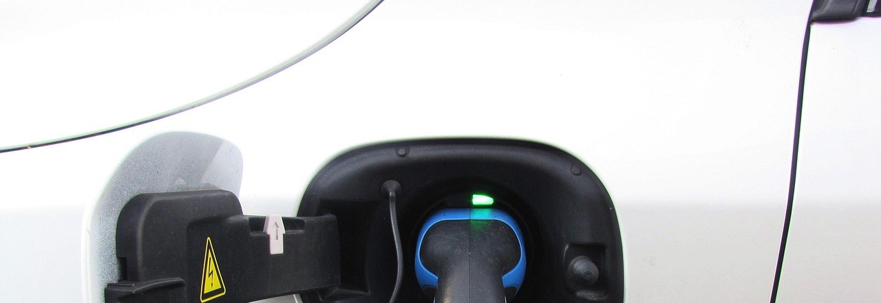 Ladestecker eines Elektroautos in der Ladebuchse, grüne Kontrolllampe leuchtet