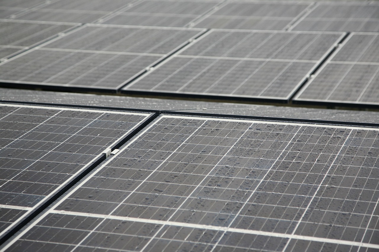 Nahaufnahme mehrerer nebeneinanderliegender Solarmodule mit Regentropfen auf der Glasoberfläche