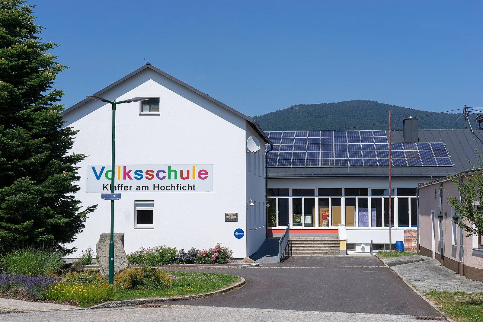 Volksschule Klaffer am Hochficht mit großem Schriftzug und Photovoltaikmodulen auf dem Dach des Anbaus.